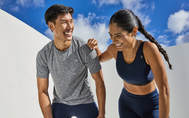 male and female laughing next to each other wearing cw-x compression gear in the color true navy